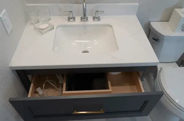 Bathroom vanity drawer with a built-in outlet and organizer under a white quartz sink top