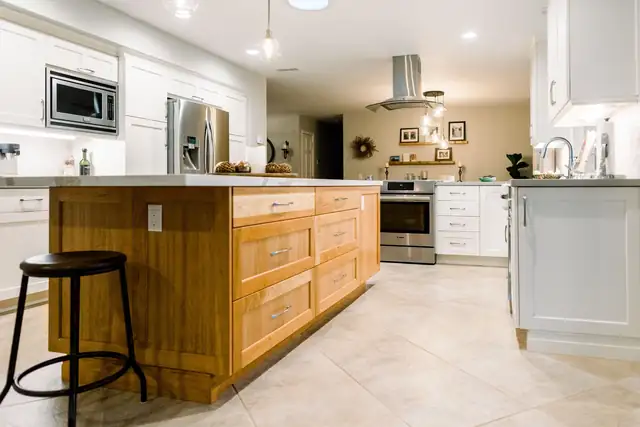 Contemporary kitchen by Kitchen Barn with a natural wood island, white cabinets, stainless appliances and a tile floor