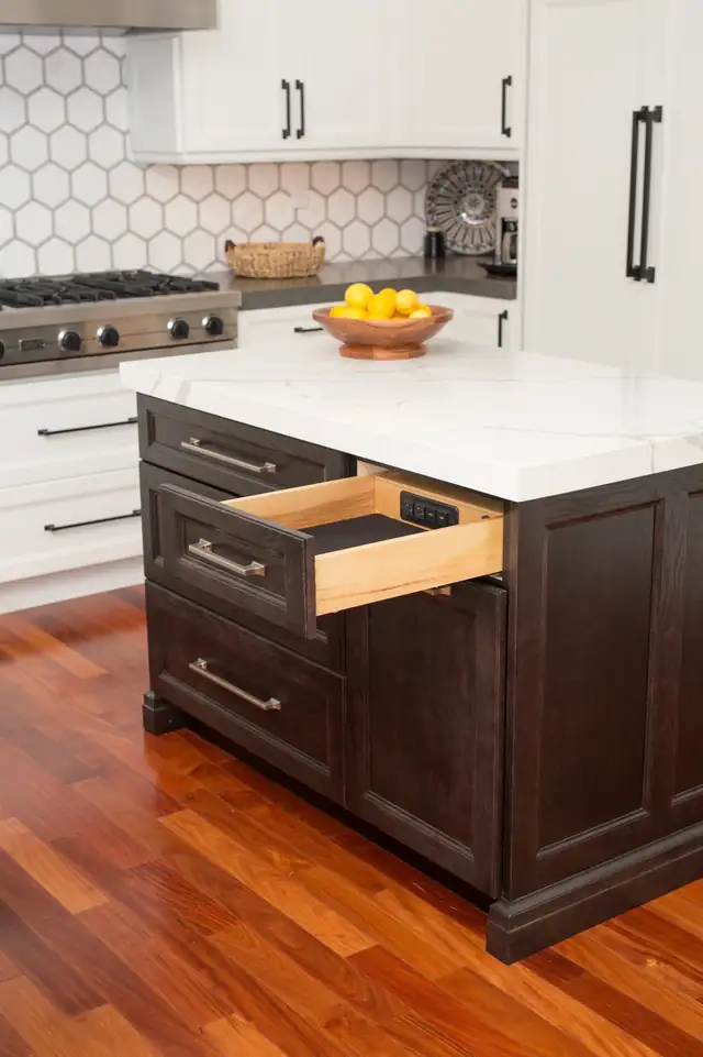Dark stained kitchen island with an open storage drawer, white quartz top and warm wood floor