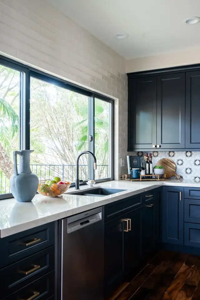 Navy kitchen cabinets with white countertop, patterned tile backsplash and a large picture window