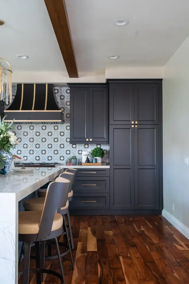 Charcoal shaker cabinets with brass hardware, blue patterned tile backsplash and walnut floors